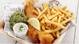 A plate of Gordon Ramsay's crispy fish and chips recipe, served with mushy peas and tartar sauce.