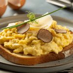 Creamy scrambled eggs topped with black truffle shavings, served on toasted sourdough with parmesan and chive garnish.